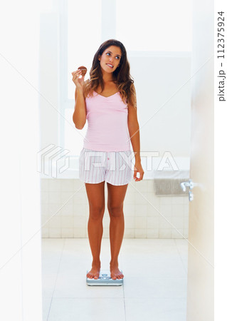 Woman, thinking and scale or weight with cake for healthy body, wellness or weightloss in bathroom at home. Person, stress or snack on weighing machine for health, goals and fitness progress in house Woman, thinking and scale or weight with cake for healthy body, wellness or weightloss in bathroom at home. Person, stress or snack on weighing machine for health, goals and fitness progress in house 112375924