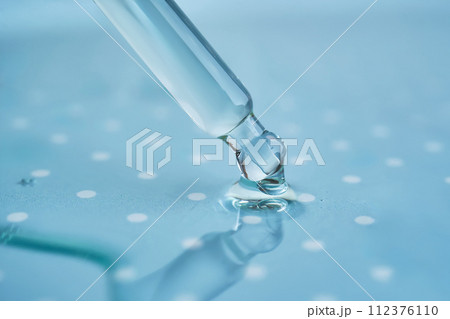 Pipette with serum on a blue background. 112376110