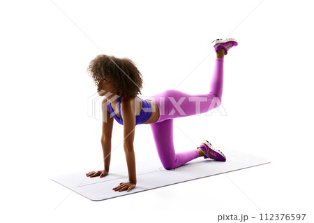 Young African-American woman training leg muscles, buttocks against white studio background. Perfect body shapes. 112376597