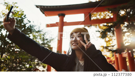 Selfie, nature and Japanese woman with peace sign for holiday, vacation and adventure in Japan. Happy, travel and person take picture on smartphone for social media post, memories and online blog 112377380