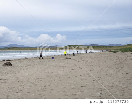 20 man are competing in a fishing competition on the beach. 112377786