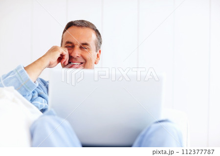 Bathrobe, relax and sofa, happy man on laptop for email, social media or streaming subscription in home. Internet search, couch and senior person on computer, website or networking in living room. 112377787