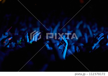 Concert, hands and audience for music with blue lights, neon and night festival, concert or psychedelic party. Crowd with arms raised with nightlife and rave or techno event for new year holiday 112378172