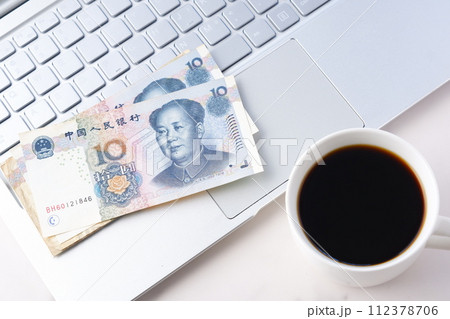 毛沢東の肖像の中国の通貨、人民元（RMB）の紙幣とノートパソコン、コーヒーが入ったコーヒーカップ 112378706