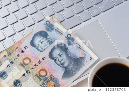 毛沢東の肖像の中国の通貨、人民元（RMB）の紙幣とノートパソコン、コーヒーが入ったコーヒーカップの写真素材 [112378708] - PIXTA