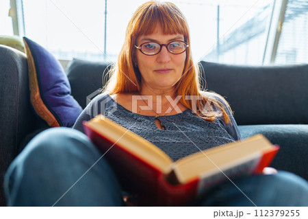 Portrait red-haired woman reading novel book Portrait red-haired woman reading novel book 112379255
