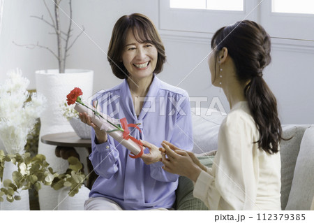 母の日　ホテルのティールームでカーネーションを渡す30代の娘と受け取る母親 112379385
