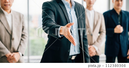 Businessman in suit extends his open palm in gesture of request and handshake, symbolizing trust successful cooperation and teamwork in office setting. It represents professionalism and confidence. Businessman in suit extends his open palm in gesture of request and handshake, symbolizing trust successful cooperation and teamwork in office setting. It represents professionalism and confidence. 112380308