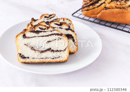 Pastry with poppy seeds, fresh bun on white plate, delicious bakery, light background, close up 112380346
