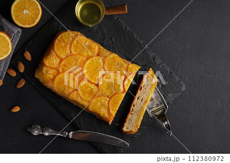Upside down orange cake on black background, copy space. Homemade cake with oranges and almond, citrus fruits. 112380972