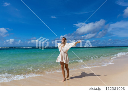 Young woman walks barefoot on the beach Young woman walks barefoot on the beach 112381008