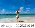 Young woman walks barefoot on the beach 112381016