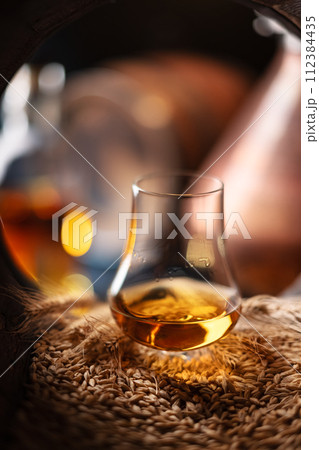 A glass of whiskey in oak barrel 112384435