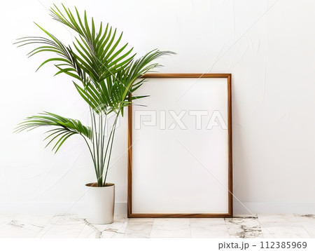 an empty picture frame on the floor, a palm plant is beside it, minimal and modern with a tropical twist 112385969