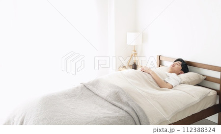 明るい部屋で寝るアジア人男性 112388324