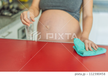 Efficient and dedicated, a pregnant woman tackles kitchen chores, ensuring a clean and organized space, exemplifying resilience and care during her pregnancy 112390458