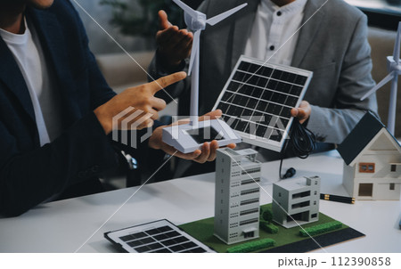 Two Young Engineers Expertise in Solar Cell Installation Meetings and Discussion in The Job. Planning to Install Solar Photovoltaic Panels on Roof Top in The Office Room with Factory Building Plan. Two Young Engineers Expertise in Solar Cell Installation Meetings and Discussion in The Job. Planning to Install Solar Photovoltaic Panels on Roof Top in The Office Room with Factory Building Plan. 112390858