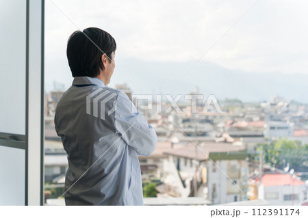 窓の外を眺める白衣姿の中年男性医師・医者・ドクター・お医者さん・医療従事者 112391174