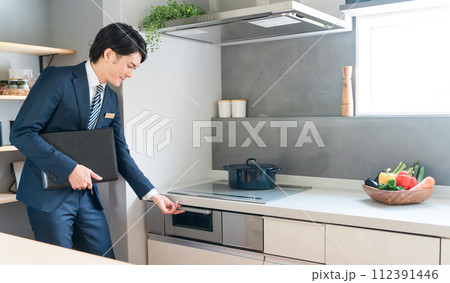 魚焼きグリル・IH調理器を案内するハウスメーカーのプランナー・コーディネーター・ビジネスマンの男性 魚焼きグリル・IH調理器を案内するハウスメーカーのプランナー・コーディネーター・ビジネスマンの男性 112391446