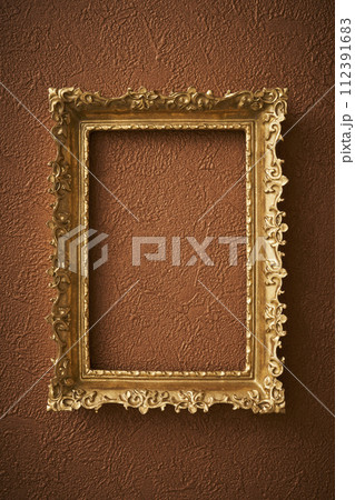 茶色い壁紙に掛けられたアンティークな額縁 112391683
