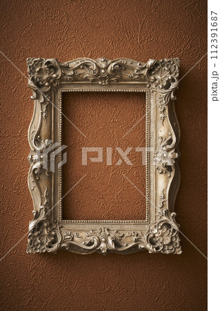 茶色い壁紙に掛けられたアンティークな額縁 112391687
