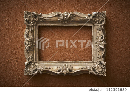茶色い壁紙に掛けられたアンティークな額縁 112391689