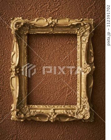 茶色い壁紙に掛けられたアンティークな額縁 112391702
