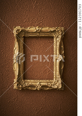 茶色い壁紙に掛けられたアンティークな額縁 112391703