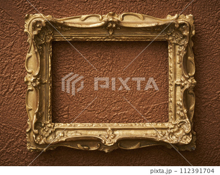 茶色い壁紙に掛けられたアンティークな額縁 112391704