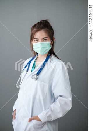Young Asian female doctor standing on grey background. 112394155