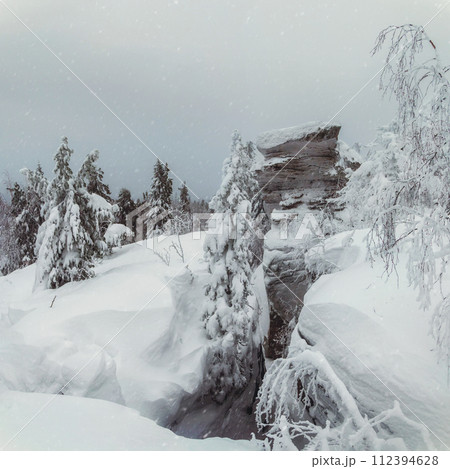 Big granite rock is frozen and covered with snow. Big granite rock is frozen and covered with snow. 112394628
