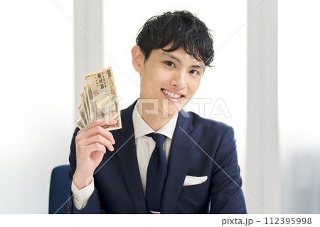 笑顔でお金を持つビジネスマン 笑顔でお金を持つビジネスマン 112395998
