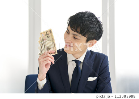 笑顔でお金を持つビジネスマン 笑顔でお金を持つビジネスマン 112395999