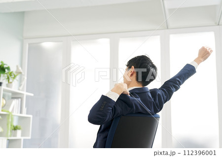 仕事中に伸びをするビジネスマン 仕事中に伸びをするビジネスマン 112396001