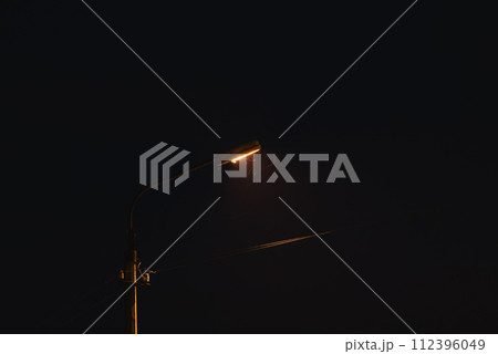 Old street lamp at night. A lantern illuminates the street in the evening. Moths fly to the light of a lantern Old street lamp at night. A lantern illuminates the street in the evening. Moths fly to the light of a lantern 112396049