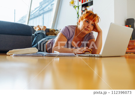 portrait woman lying on parquet floor with laptop, notebooks, emotions on face portrait woman lying on parquet floor with laptop, notebooks, emotions on face 112396073