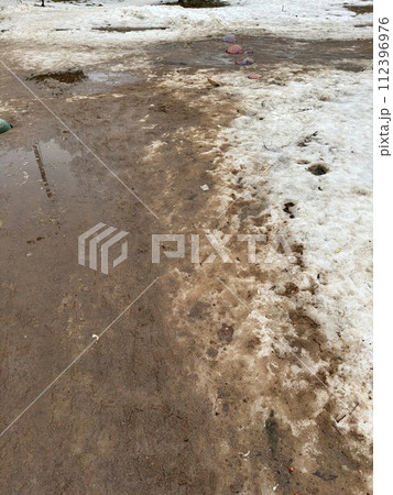 Melting dirty snow on the streets of the city during the daytime in winter. Snow with sand and mud lies on the road Melting dirty snow on the streets of the city during the daytime in winter. Snow with sand and mud lies on the road 112396976