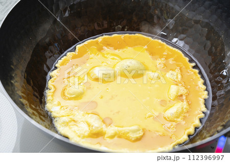 鉄製の鍋で卵を炒める 112396997