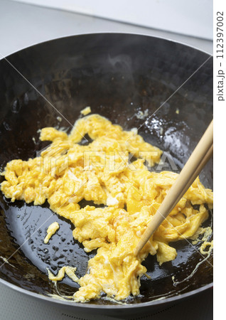 鉄製の鍋で卵を炒める 鉄製の鍋で卵を炒める 112397002