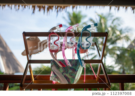 テラスに干されたシュノーケルセットと水着と麦わら帽子 112397008