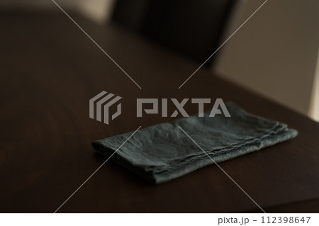 Dark green linen napkin on walnut table indoor with natural window light Dark green linen napkin on walnut table indoor with natural window light 112398647