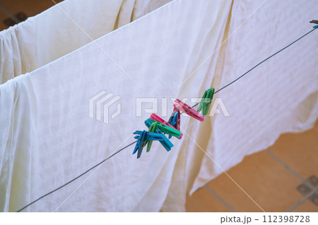Colorful clothes after washing are hung on a clothesline to dry in the wind, bed linen, sheets, towels. Household hygiene items 112398728