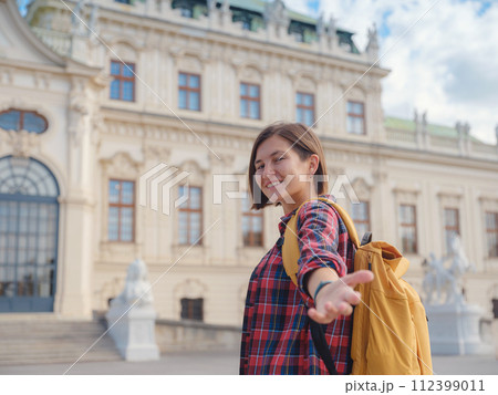 Female tourist traveling in Austria, capital city Vienna. summer female solo trip to Europe, happy young woman walking in park near Belvedere palace complex in Baroque style. Female tourist traveling in Austria, capital city Vienna. summer female solo trip to Europe, happy young woman walking in park near Belvedere palace complex in Baroque style. 112399011