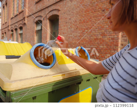 woman throwing plastic bottle Recycling bin stand on european street. Waste separation rubbish before drop to garbage bin to save world, environment care. Pollution trash recycling management concept woman throwing plastic bottle Recycling bin stand on european street. Waste separation rubbish before drop to garbage bin to save world, environment care. Pollution trash recycling management concept 112399118