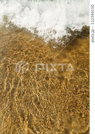 sandy beach with waves rolling in, creating a beautiful natural background. beige sand contrasts with ocean waves. concept for perfumes, smells, heat, freshness, coolness and other associations sandy beach with waves rolling in, creating a beautiful natural background. beige sand contrasts with ocean waves. concept for perfumes, smells, heat, freshness, coolness and other associations 112399150