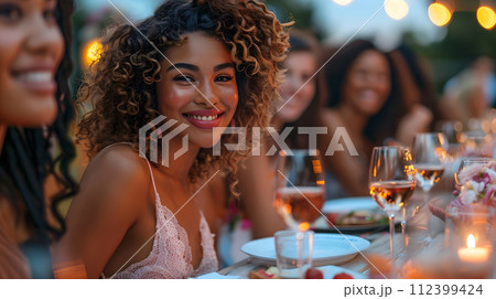Beautiful women smiling at dinner and wine party in the garden along with other women with a blurry background wear simple and elegant clothes. Enjoy fun conversations and share memorable experiences. 112399424