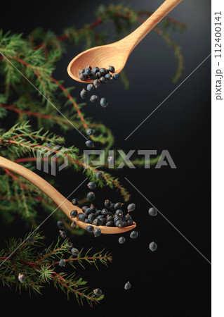 Juniper seeds are sprinkled with a wooden spoon. Juniper seeds are sprinkled with a wooden spoon. 112400141