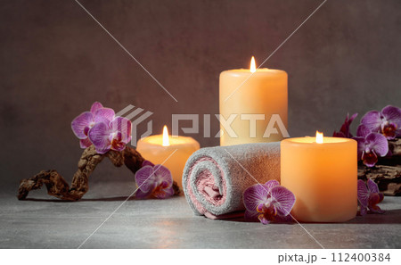 Towels, orchid flowers, and burning candles. 112400384