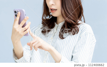 スマートフォンを見て驚く女性 112400662