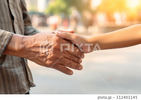 A grandparent and grandchild handshake captured in a city environment. 112401145